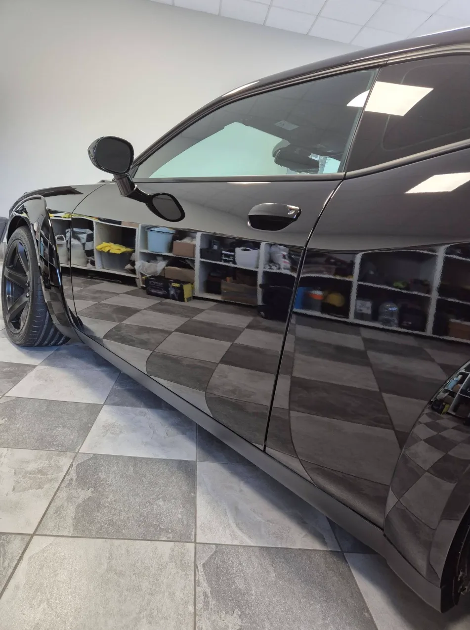 Juodas Dodge Challenger, kurio šone atsispindi studijos lentynos